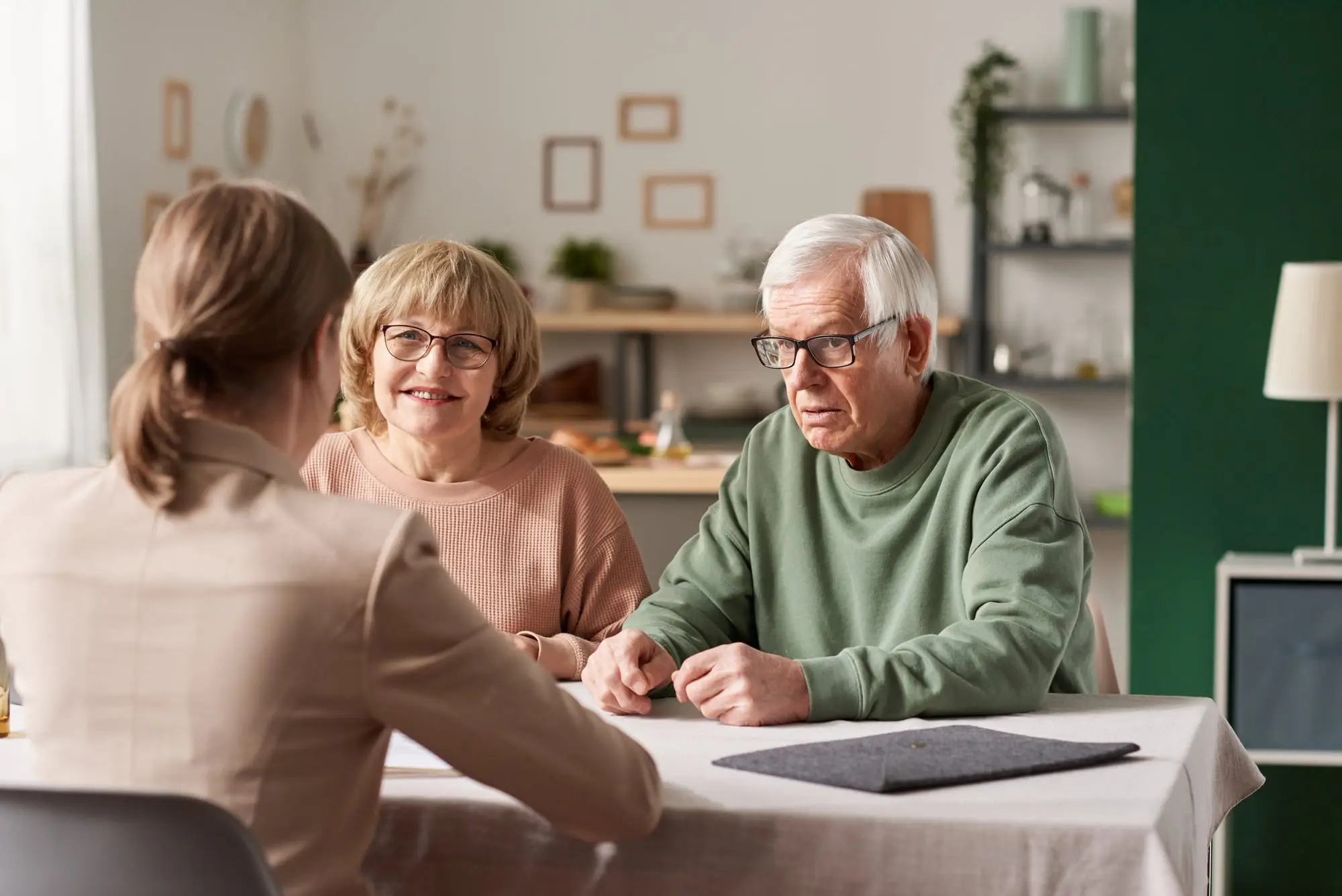 An older couple at their dining table, talking a decision through with an advisor