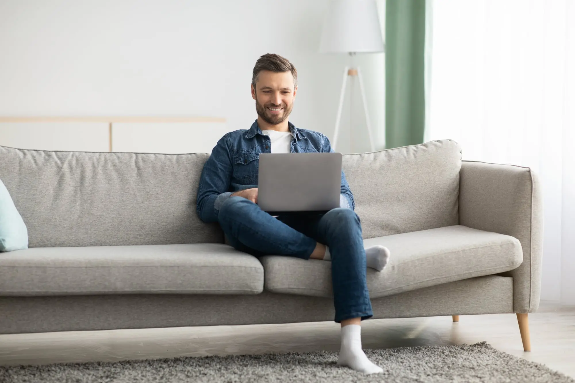 A man on his sofa at home using his laptop